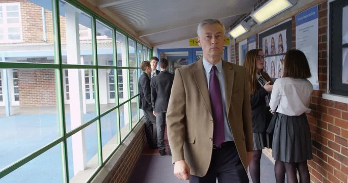 4K Strict teacher walking through school building & disciplining young teen students