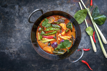 Traditional Thai kaeng phet red curry with vegetables as top view in a wok with copy space left - obrazy, fototapety, plakaty