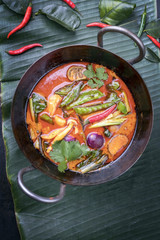 Traditional Thai kaeng phet red curry with vegetables as top view in a wok on a banana leaf