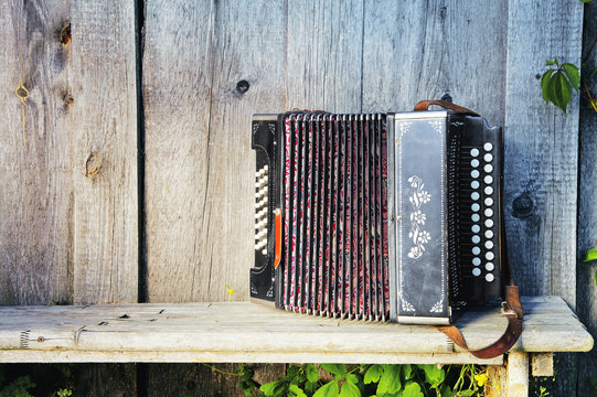 Old lonely accordion on the bench in summer sunny weather