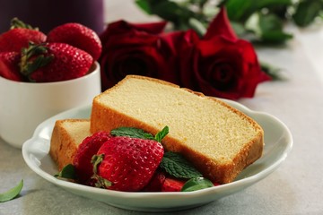 Two slices of butter cake served with berries and red roses in background