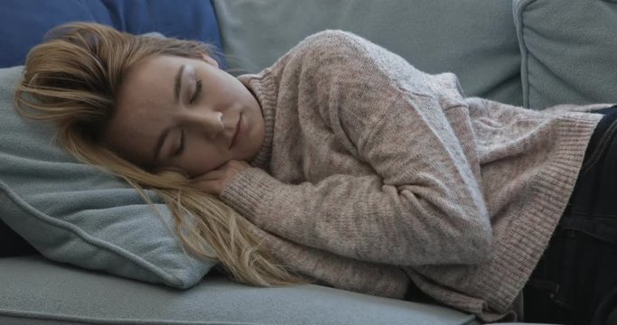 Young sleepy woman falling down on sofa at home.
