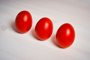 Easter decoration with three red eggs on a white wooden table