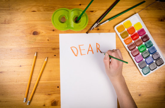 kids hand drawing a greeting on blank page, top view