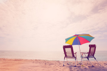 Two deck chairs under sun umbrella on the beach