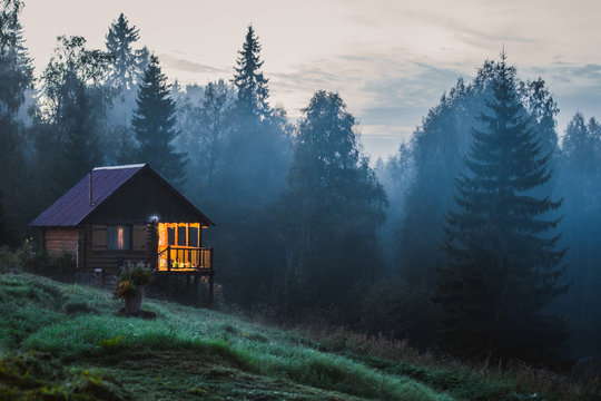  Сute rustic wooden house in the fog near the forest. Small old wooden house in foggy forest. Mountains scenery. Nature conceptual image.
