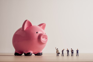 Conceptual image of business people looking at giant Piggy Bank