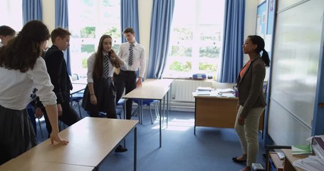 4K Tracking shot of happy students leaving classrooms in groups & walking through school building