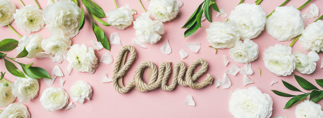 Saint Valentines Day background. Flat-lay of white ranunculus flowers and word love over light pink...