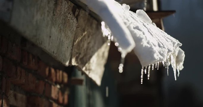 Rack focus, snow melts on roof