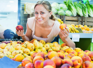 Obraz premium Woman customer choosing peaches on fruit market