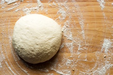 raw pizza dough on wooden background