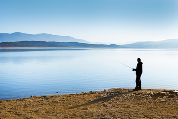 Fisherman silhouette at the background of beautiful sunset lake scenery in Bulgaria, Europe.