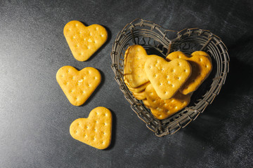 Obraz premium A heart cookie, in a vase in the shape of a heart on a dark background. A metal vase with cookies. Love.