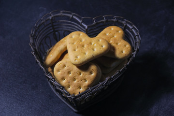 A heart cookie, in a vase in the shape of a heart on a dark background. A metal vase with cookies. Love.