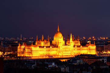 Obraz premium Panorama of Neo-Gothic Orszaghaz Parliament Building Hungarian legislative body seat at dusk illuminated by glowing yellow light on Danube riverbank Kossuth Square Pest Budapest Hungary Central Europe