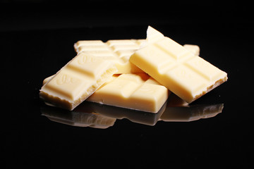 White chocolate bar on black reflective studio background. Isolated black shiny mirror mirrored background for every concept.