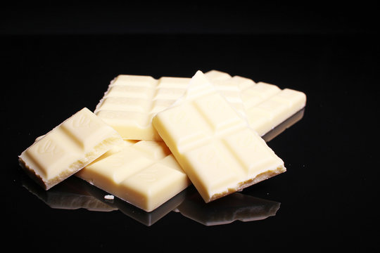 White chocolate bar on black reflective studio background. Isolated black shiny mirror mirrored background for every concept.