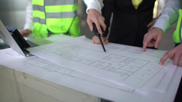 Close up hands of three workers or engineers discussing building drawings in office. Closeup shooting of arms moving pictures, watching attentively on images. design drafts for construction of large