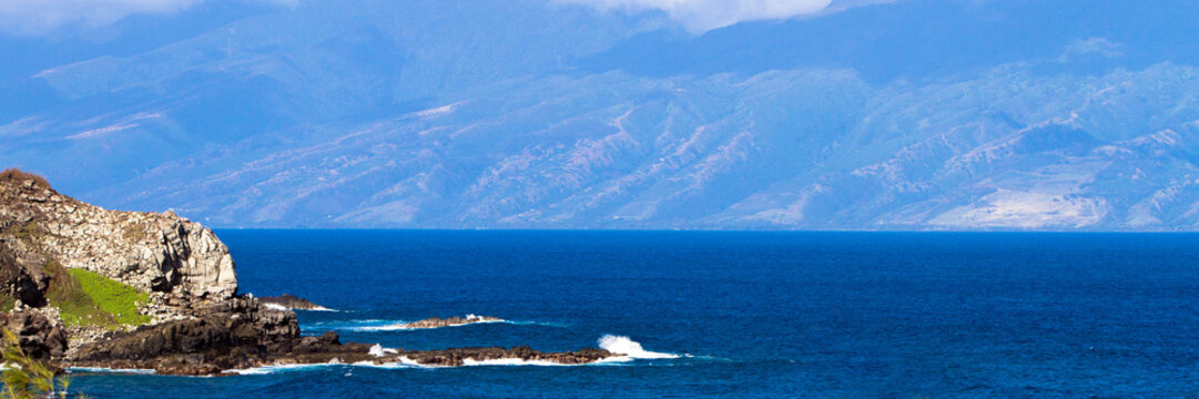 Panorama of volcanic rock and Pacific surf on the coast of Maui, Hawaii, with Molokai in the distance
