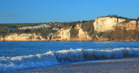 Wave during high tide with Beer Head in background on Jurassic Coast