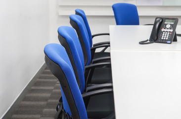 blue chair with IP phone on white meeting table in office
