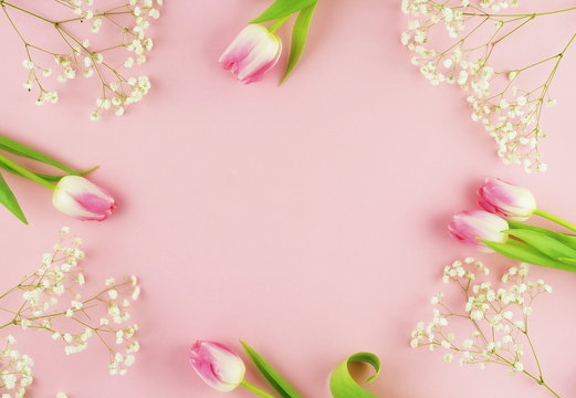 Frame of pink tulips and white flowers on a pale pink background.Holiday concept. Copy space. Top view
