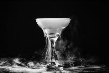 Closeup wine glass with white fog at dark background. Chemical reaction of dry ice with water.