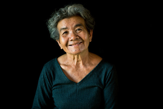 Happy Asian old woman smiling and joyful on black background