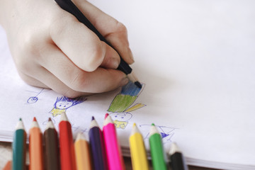 The child draws with colored pencils. Children's creativity