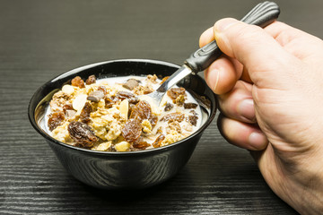 Quick healthy breakfast. Bowl with roasted crunchy cocoa muesli with peanuts, milk chocolate, caramel and raisins with milk.
