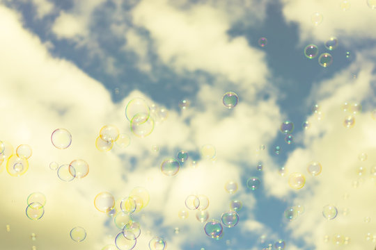 Abstract background : Beautiful soap bubbles reflecting various color floating on sky and white cloud background.