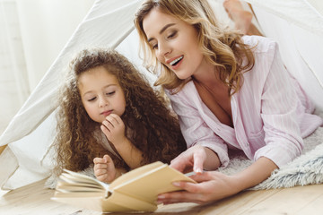 beautiful mother and daughter reading book in kid wigwam © LIGHTFIELD STUDIOS