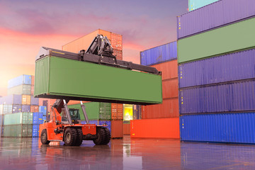 Industrial background of container depot and reach stacker is working to carry green container...