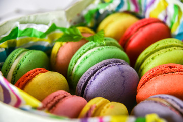 colorful macaroons in a gift box with a bright paper on a light background
