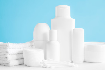 Different, white beauty toiletries, cotton wools and towels on blue background. Body relax and care products for women and men. Front view.