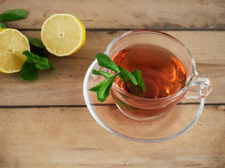 Side view tea cup with slices of lemon and mint leaves, with rustic background