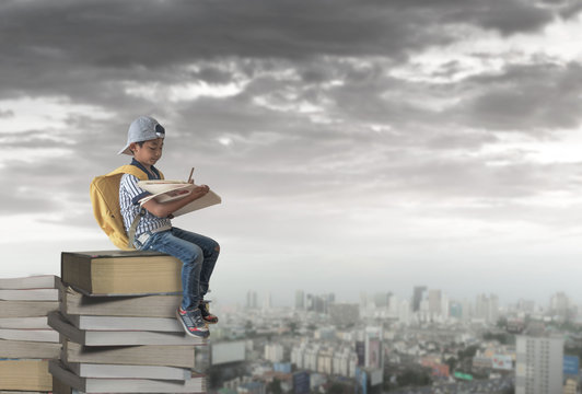 Child Sitting On A Stack Of Books With Drawing In The Book.