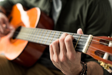 cropped image of man playing chord on acoustic guitar