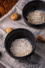 Flakes of wheat porridge. Still life on a wooden background with walnuts.