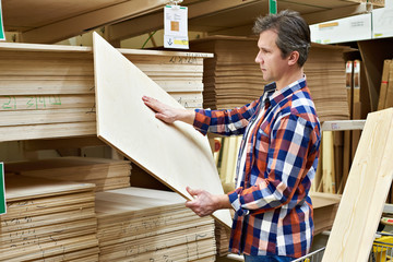 Man chooses plywood boards in store - obrazy, fototapety, plakaty