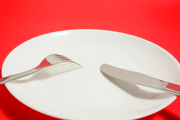 a white dish and a fork and a knife   白いお皿とナイフとフォーク　赤色背景