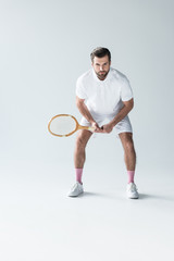 handsome tennis player with tennis racket on grey