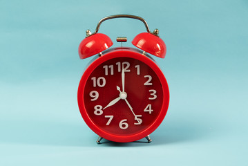 Red alarm clock on blue pastel background