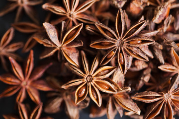 Obraz premium Anise stars closeup in wooden bowl on dark background