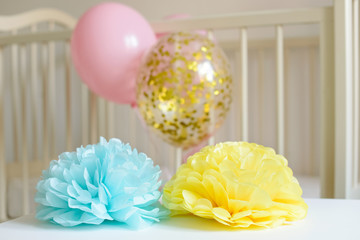 Various festive paper decor and balloons in front of baby bed. Baby bedroom interior. Baby birthday celebration concept.