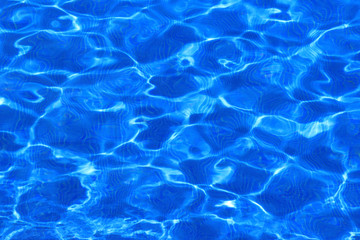 Fototapeta na wymiar Blue pool water with big ripples and small waves in the sun