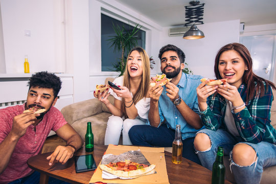 Group Of Young Friends Eating Pizza And Watching Tv.Home Party.Fast Food Concept.