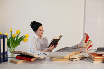 beautiful girl reads books at the table preparing for the exam