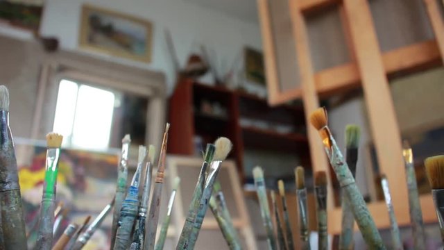 Artistic studio. Oil paintings. The canvas on the easel. Set of various sized dirty brushes. Fine art painting